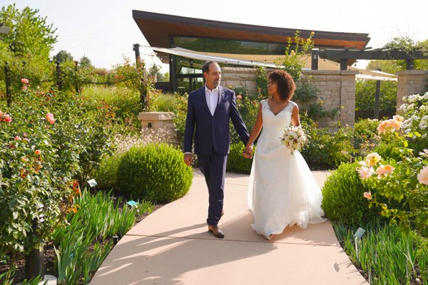 A bride and groom walking hand in hand in the Rose Garden at Red Butte Garden