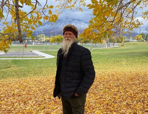 James Batton in autumn leaves with mountains in the background