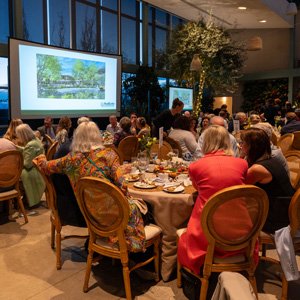 Guests seated around tables at a party in the Red Butte Garden Orangerie