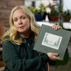 woman holding the book called The Forgotten Garden