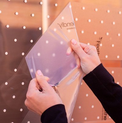 A person applying bird strike prevention dots to a window